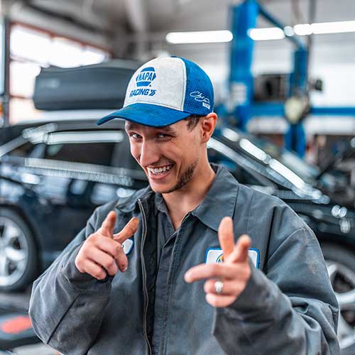 Smiling mechanic in garage with blue cap.