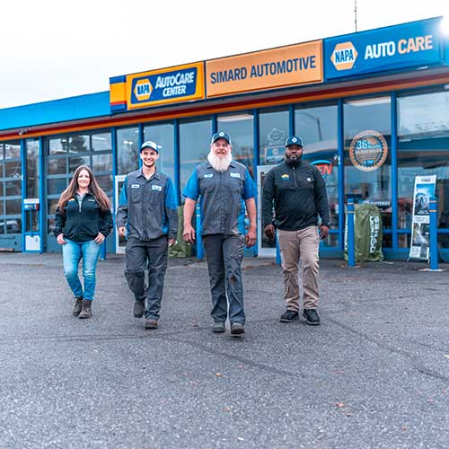 Four employees outside NAPA AutoCare Center building.